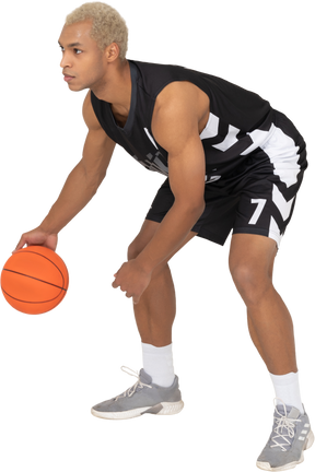 Dreiviertelansicht eines jungen männlichen basketballspielers beim dribbeln