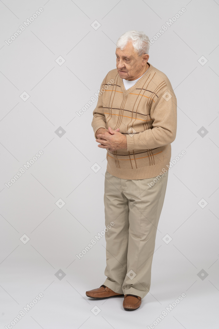 Vista frontal de un anciano con ropa informal mirando algo con interés
