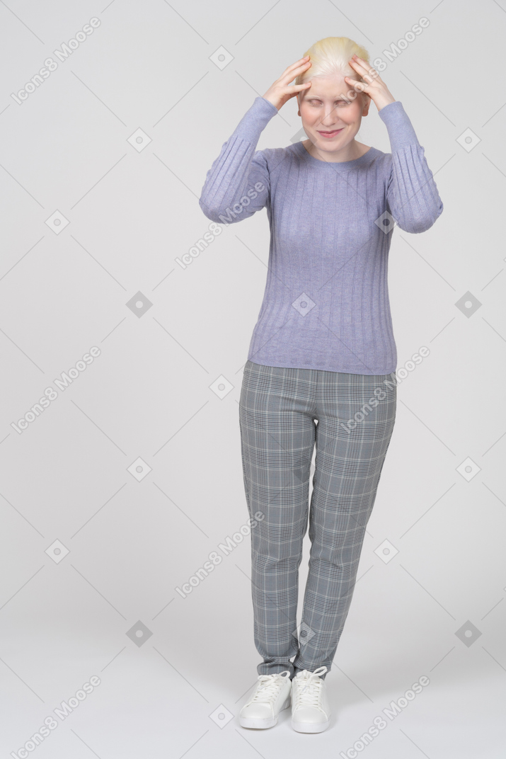Smiling woman in casual clothing touching top of head