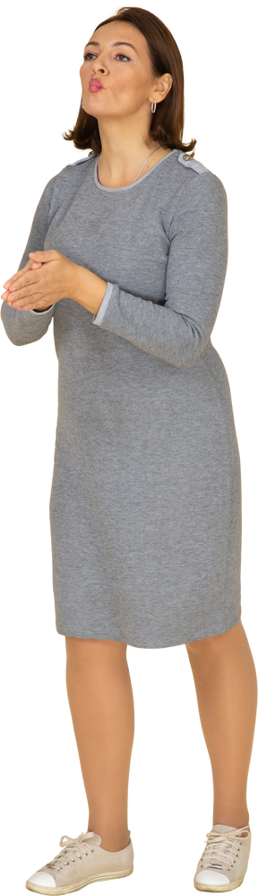 Vista frontal de uma mulher de vestido cinza fazendo caretas