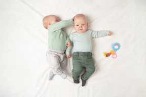 Младенцы близнецы лежат на спине рядом друг с другом