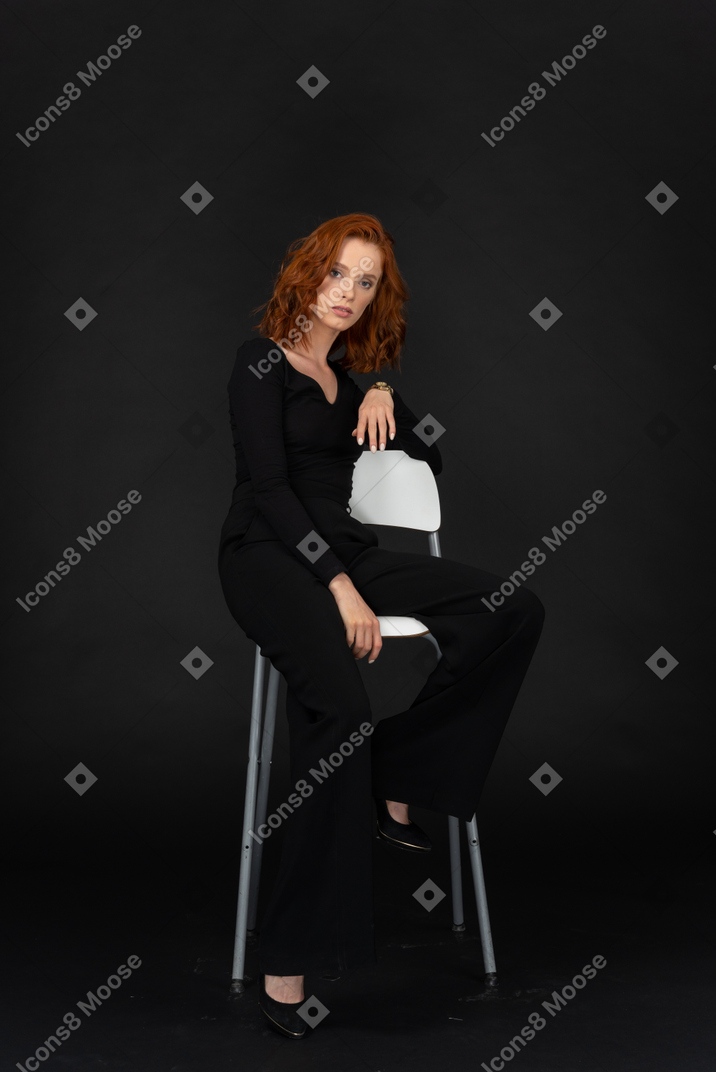 Элегантная женщина в черной одежде сидит на стуле