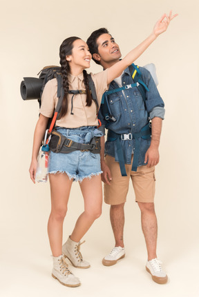 Young female traveller pointing at something to her boyfriend