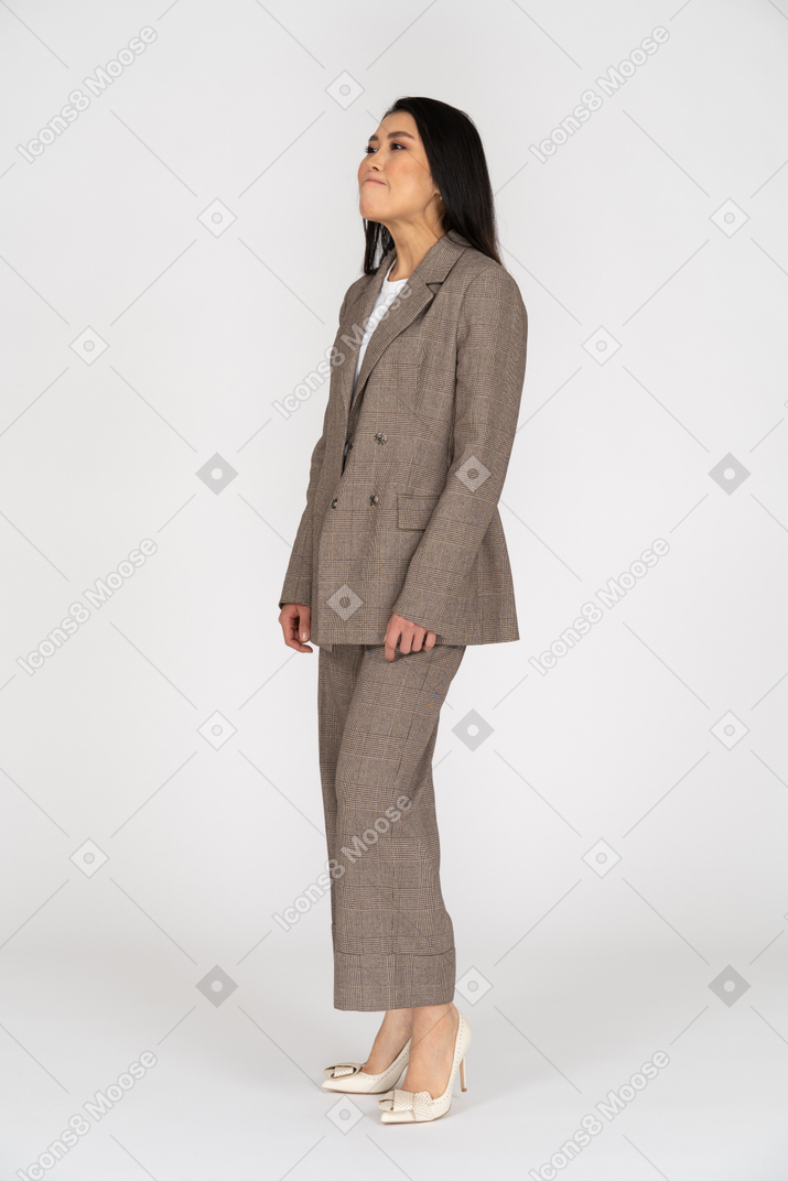 Three-quarter view of a grimacing young lady in brown business suit looking up