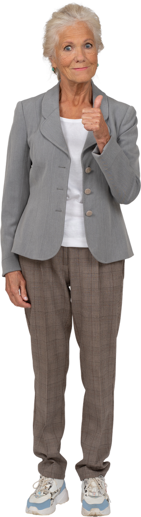 Vista frontal de una anciana feliz en traje mostrando el pulgar hacia arriba