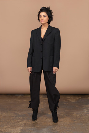 Vista frontale di una donna d'affari scontenta in un abito nero che osserva da parte