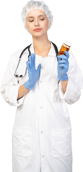 Вид спереди молодой женщины-врача, держащей банку таблеток