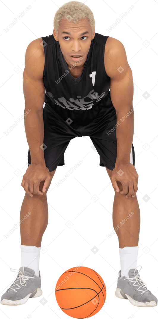 Vue de face d'un jeune joueur de basket-ball masculin debout près de la balle