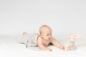 Baby girl covered in towel and looking on stuffed toy