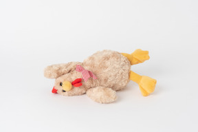 Un juguete de gallina de peluche acostado aislado contra un fondo blanco liso