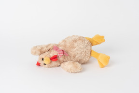 A plush chicken toy lying isolated against a plain white background