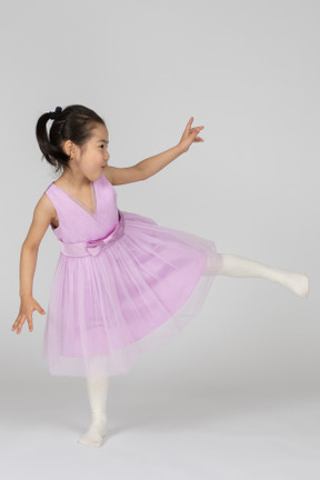 Girl in a pink dress standing on one leg