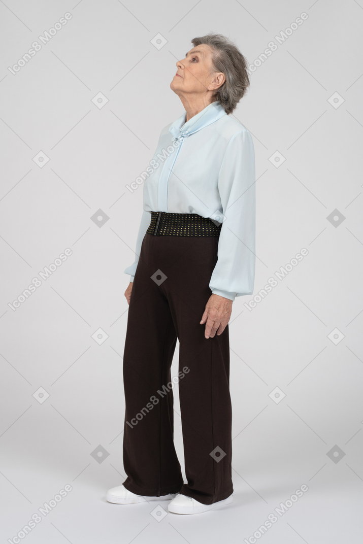 Vista di tre quarti della donna anziana in piedi con la testa in su