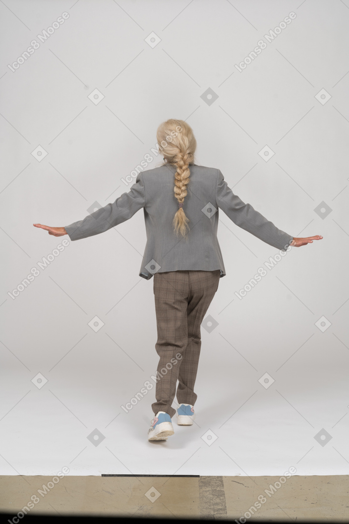 Back view of an old lady in suit outstretching arms