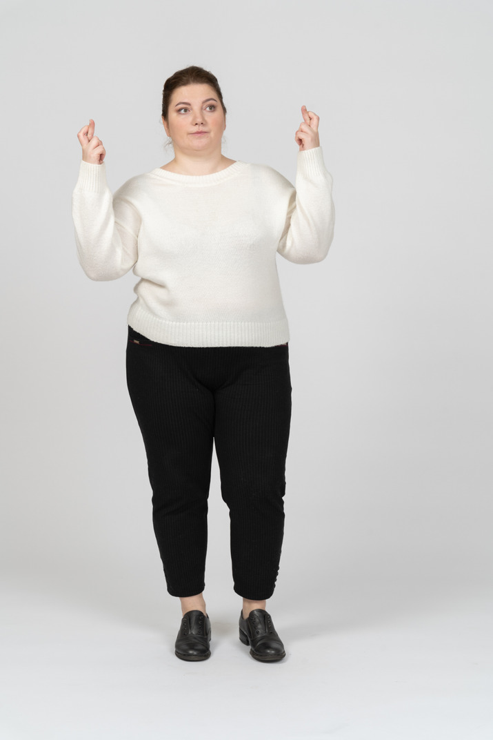 Front view of a plus size woman in white sweater crossing fingers