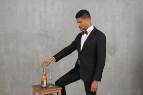 Man standing and looking down at a champagne bottle