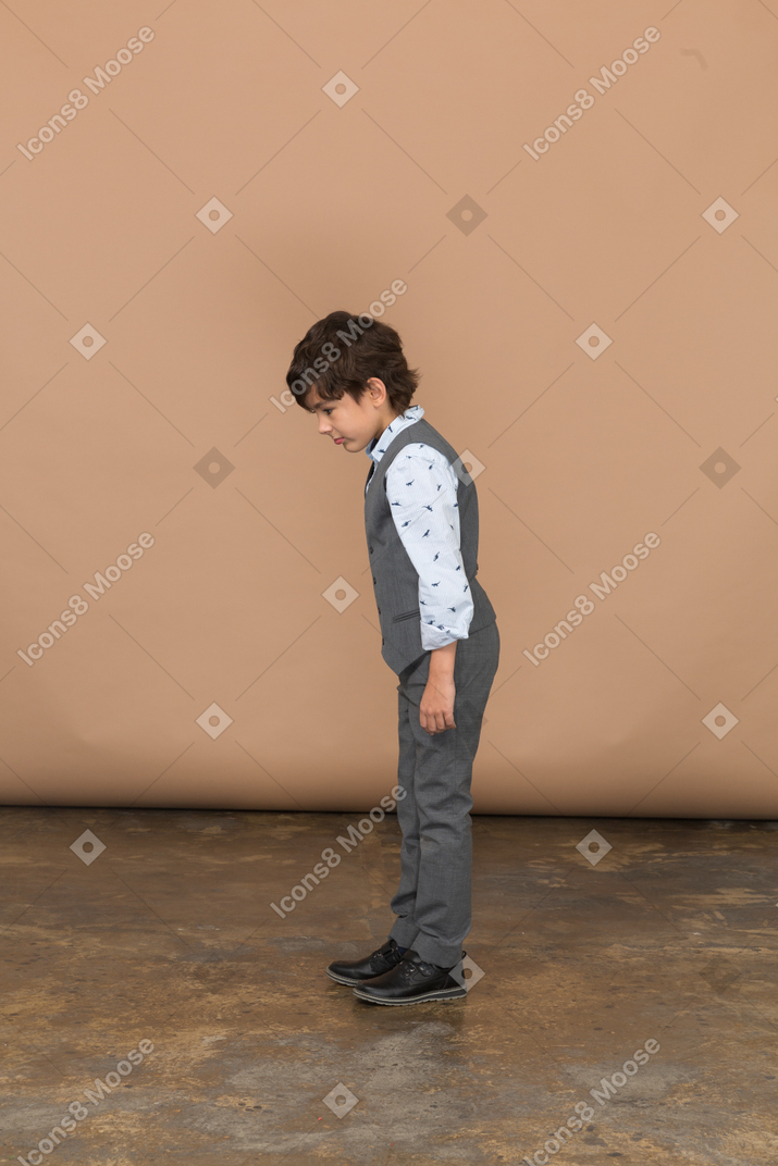 Side view of a cute boy in grey suit looking down