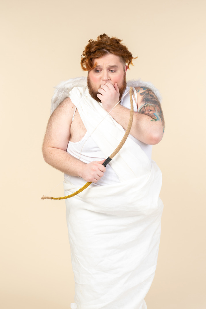 Worried big guy dressed as a cupid holding bow and arrow