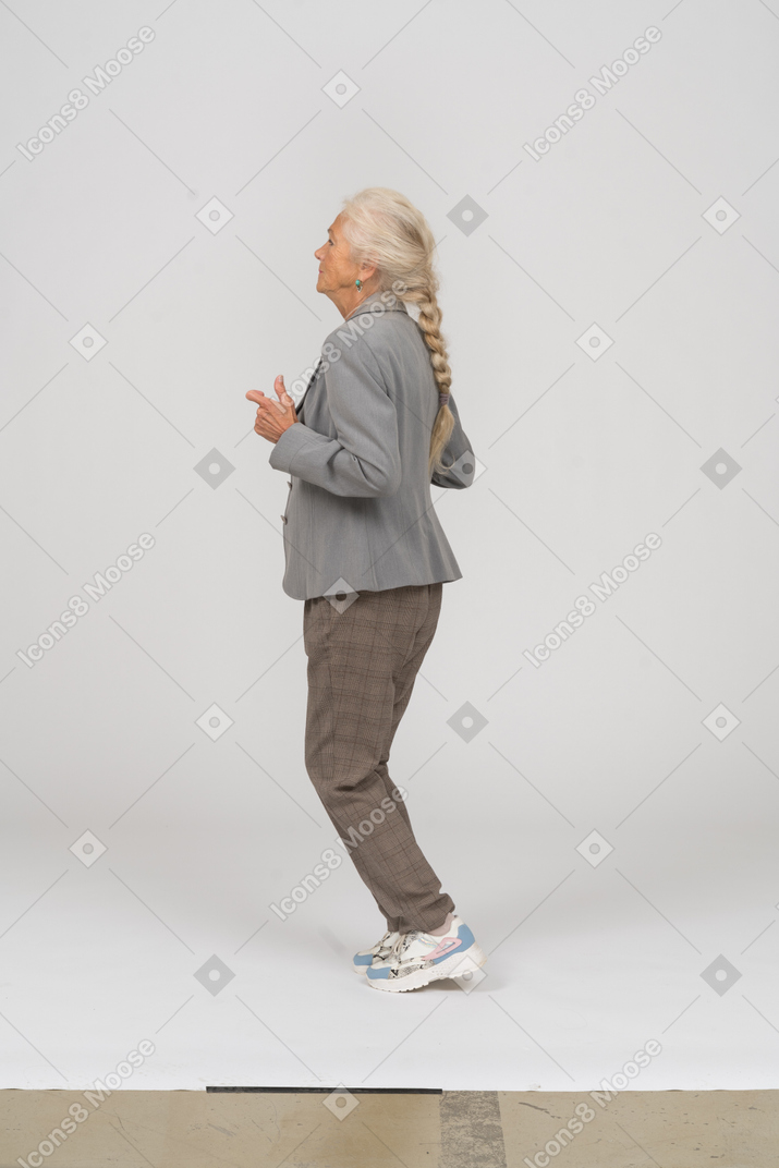 Vista laterale di una vecchia signora in abito in piedi sulle punte dei piedi