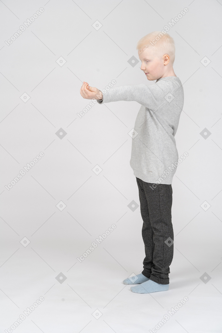 Vista lateral de um menino segurando a mão vazia
