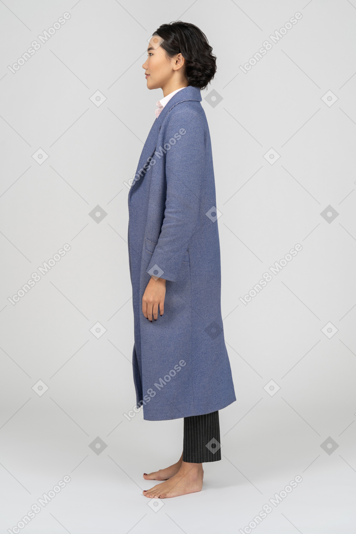 Vista lateral de uma mulher em pé de casaco azul