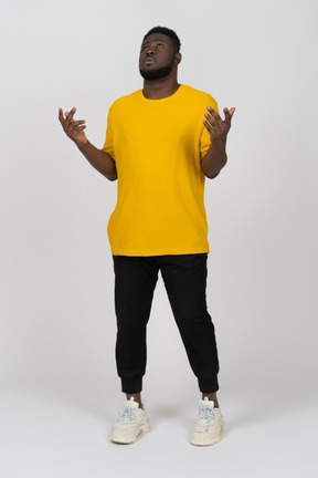 一个身穿黄色 t 恤、站着不动的黑皮肤年轻男子的前视图