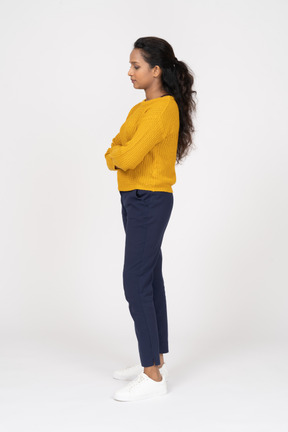 Side view of a girl in casual clothes posing with crossed arms