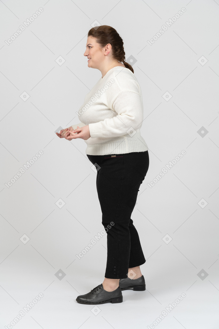 Plump woman in white sweater standing in profile