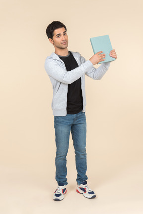 Young caucasian man pointing at book he's holding