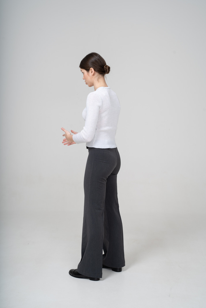 Young woman in black pants and white blouse standing in profile
