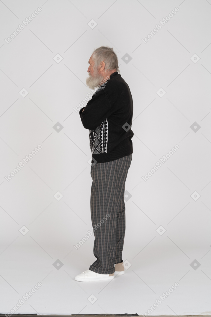 Vista lateral del anciano de pie con los brazos cruzados