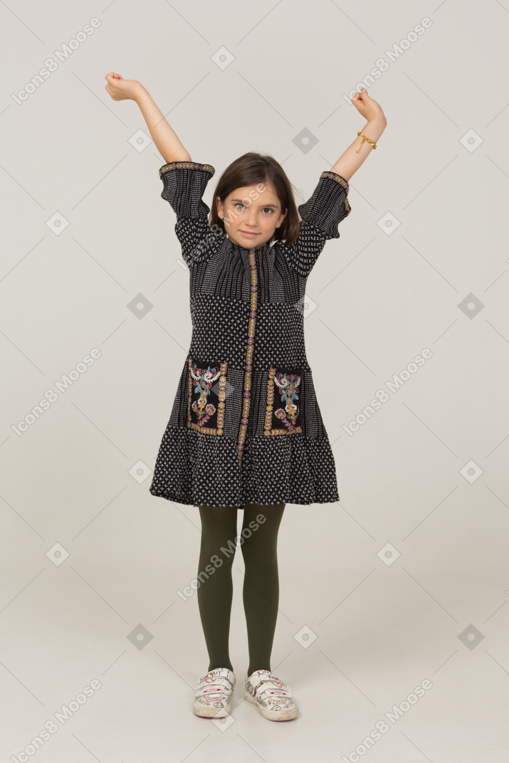 Vista frontale di una bambina in abito che alza le mani
