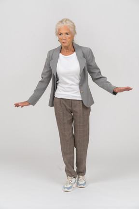 Vista frontale di una vecchia signora in abito in piedi con le braccia tese