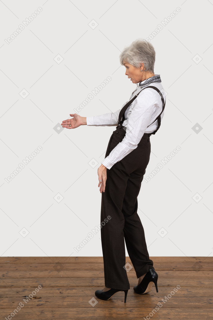Side view of a questioning old lady in office clothing outstretching her hand