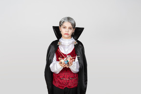 Boy in vampire costume holding candies