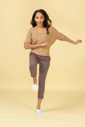 Vista frontal de una mujer joven de piel oscura marchando levantando la pierna
