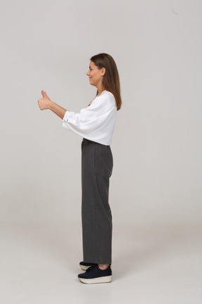 Vista laterale di una giovane donna in abiti da ufficio che mostra i pollici in su