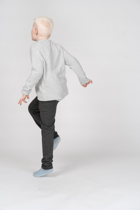 Vista posteriore di tre quarti di un ragazzo in piedi su una gamba sola