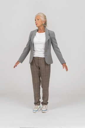 Front view of an old lady in suit standing on toes and outspreading arms