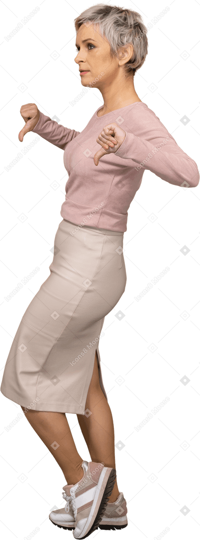 Vista lateral de una mujer en ropa casual mostrando los pulgares hacia abajo