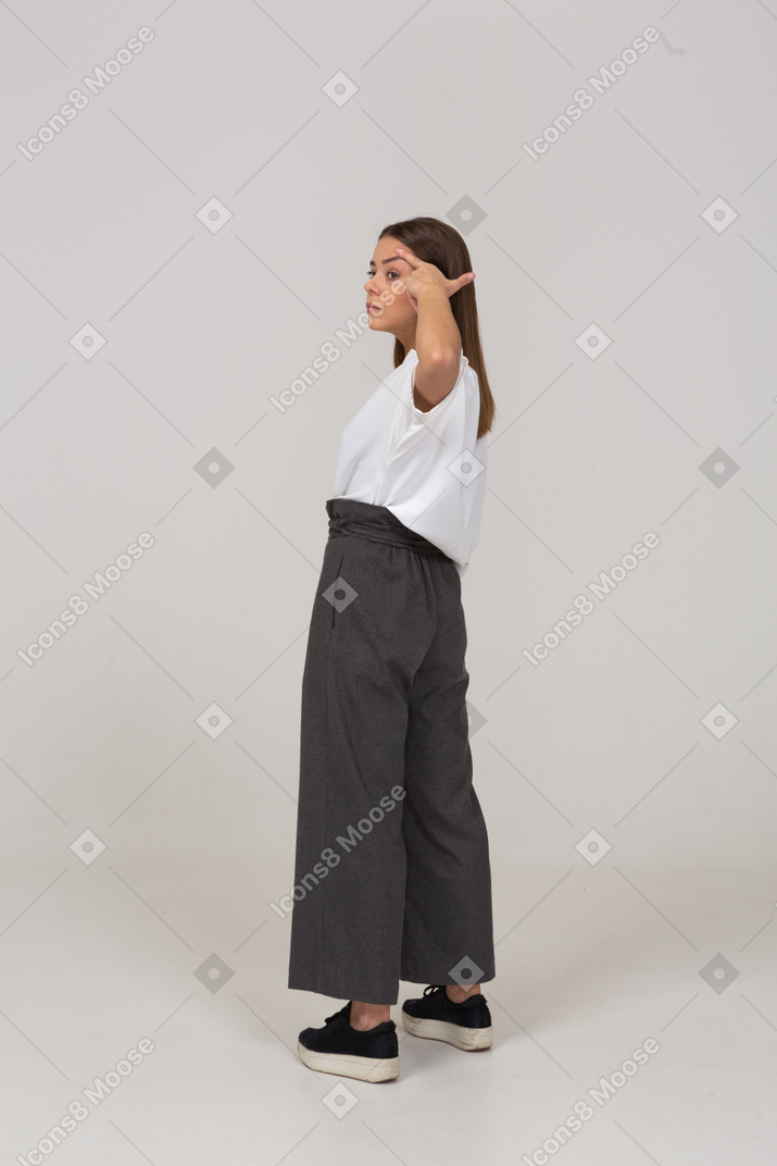 Three-quarter back view of a young lady in office clothing looking aside & touching head