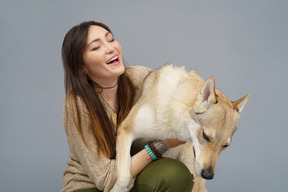 Primo piano di un maestro femminile che sorride e che abbraccia il suo cane