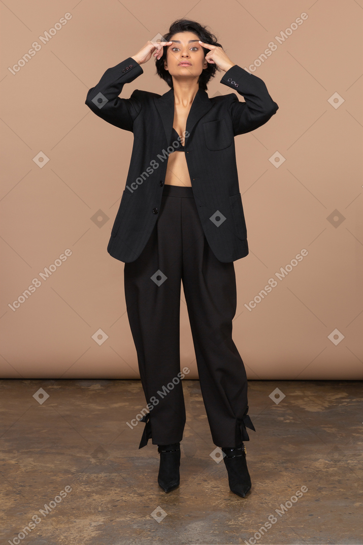 Front view of a tired businesswoman pointing fingers to her head ang looking at camera