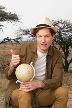 A man in a hat is holding a globe