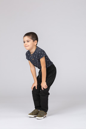 Vista lateral de un chico lindo en cuclillas y tocando las rodillas