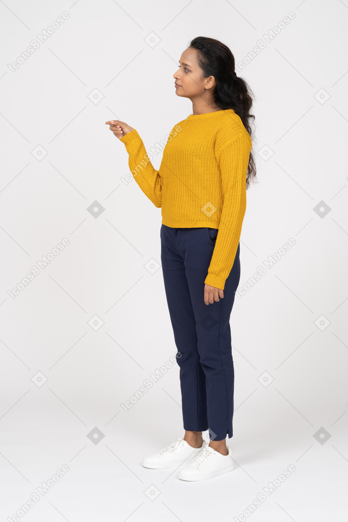 Side view of a girl in casual clothes standing with raised hand