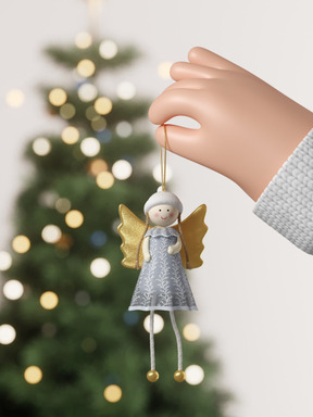 Mano poniendo un adorno de ángel en el árbol de navidad