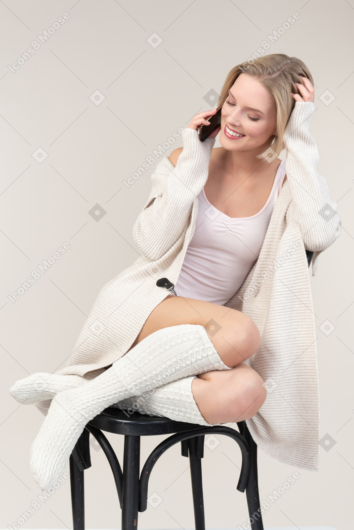 Involved in phone conversation young woman sitting on chair