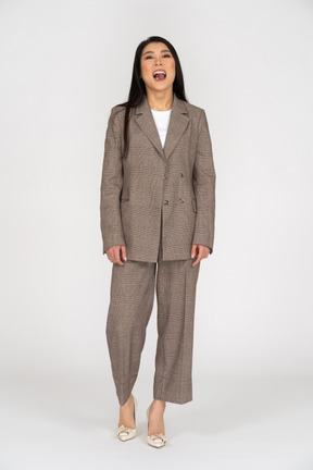 Front view of a smiling young lady in brown business suit showing tongue