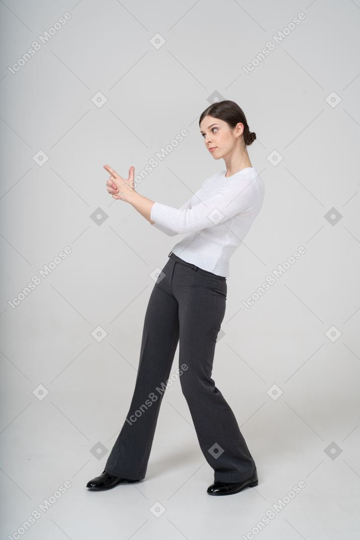Side view of woman pointing with finger gun